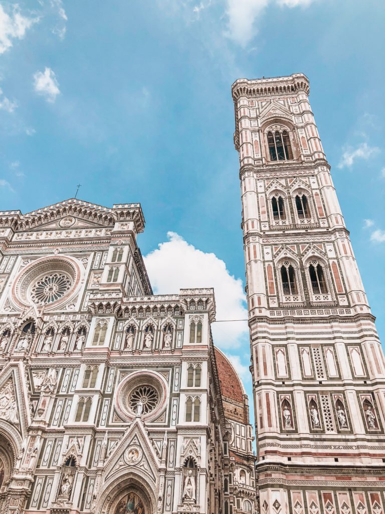 The Perfect 3 Day Florence Itinerary (From an Italy Travel Expert) 11 Close-up detail of the Florence Duomo, the Cathedral of Santa Maria del Fiore, showing the intricate pink, white and green marble exterior paneling with geometric diamond patterns, carved stone reliefs and decorative arched niches on the lower facade