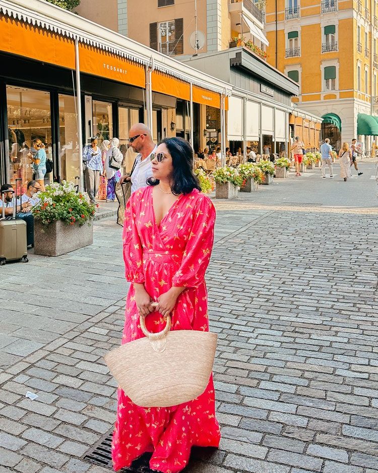 Bellagio Or Varenna: Where To Stay & Which Is Better? 19 woman wearing a pink maxi dress infront of colorful buildings of Bellagio, Lake Como