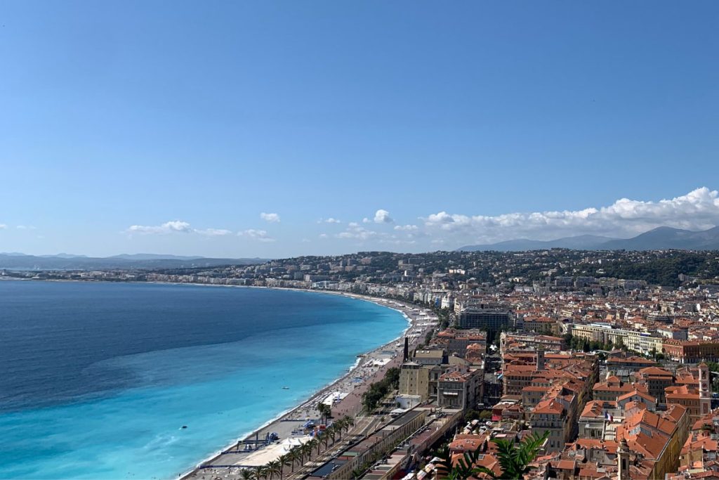 34 Incredible Weekend Trips From Barcelona 37 Breathtaking view from Castle Hill of the curved Baie des Anges and the terracotta rooftops of Nice, France, with the azure blue waters of the Mediterranean Sea and the backdrop of the Alps under a clear sky.