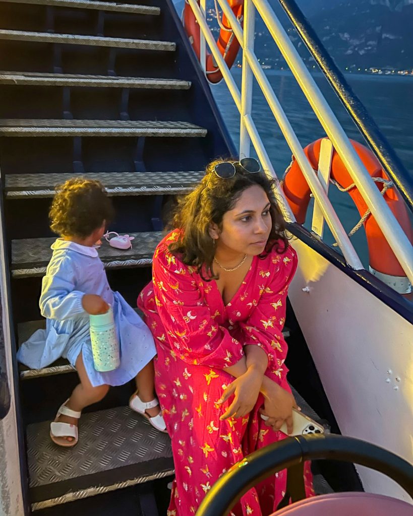 Bellagio Or Varenna: Where To Stay & Which Is Better? 31 Woman in pink dress and toddler baby girl in blue dress sitting on the stairs of a ferry in Lake Como
