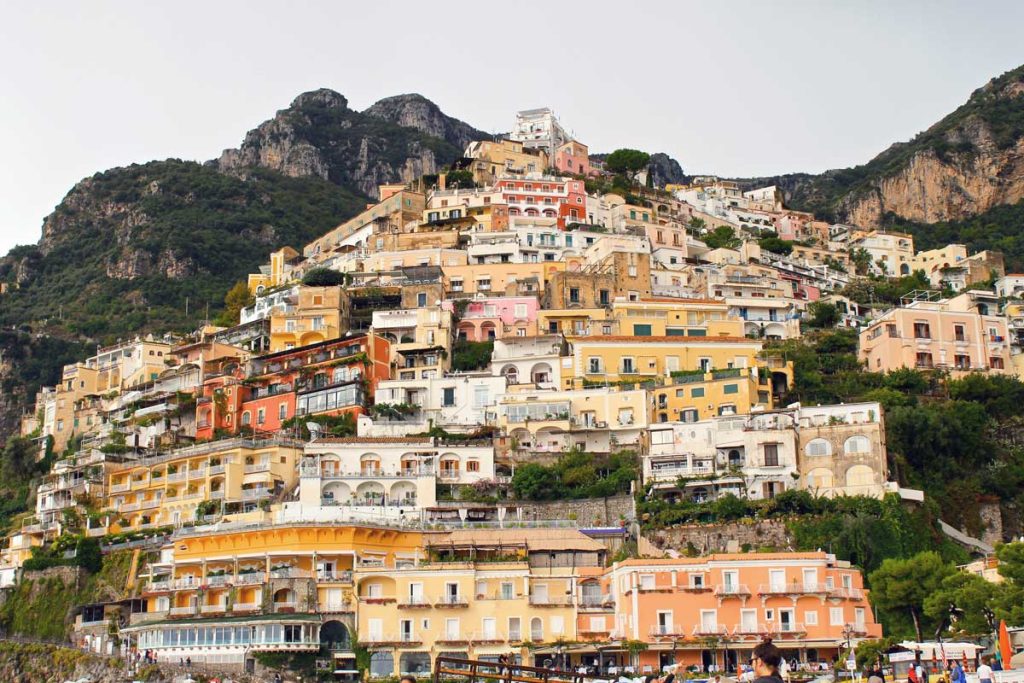The Most Luxurious 5 Day Amalfi Coast Itinerary 20 A close-up of Positano's iconic colorful houses stacked on a steep cliffside, showcasing vibrant architectural details surrounded by lush greenery.