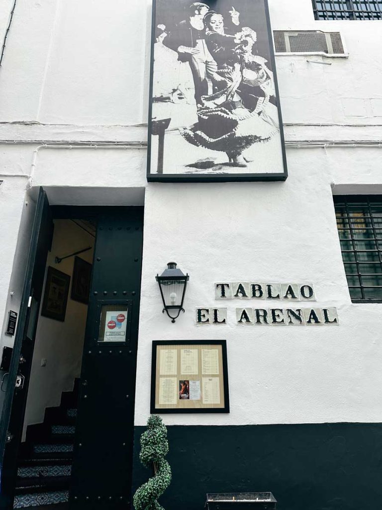 3 Most Amazing Days In Seville, Spain 26 Street view of the entrance to Tablao El Arenal, a flamenco venue in Seville, with a vintage photo of dancers above the door and a menu posted beside the entrance.