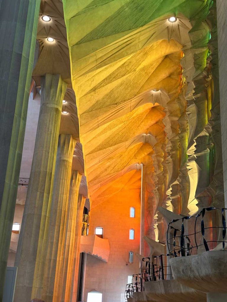 3 Days in Barcelona: The Perfect Itinerary for First-Time Visitors 16 A mesmerizing interior shot of La Sagrada Familia, where sunlight streams through stained-glass windows, casting vibrant green, yellow, and orange hues onto the intricately designed ceiling and towering columns.