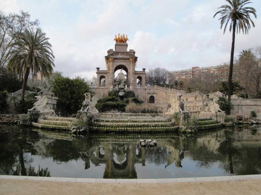 3 Days in Barcelona: The Perfect Itinerary for First-Time Visitors 44 A serene view of the Cascada Monumental, an ornate fountain in Parc de la Ciutadella. The fountain features grand sculptures, cascading water, and a golden chariot statue atop an arched structure, with palm trees and greenery in the background.