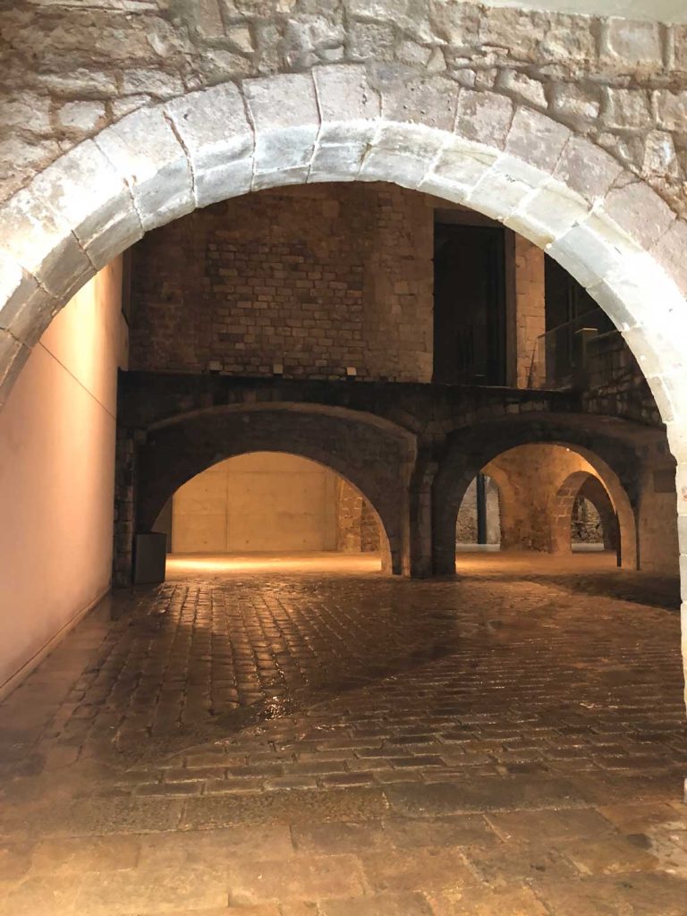 3 Days in Barcelona: The Perfect Itinerary for First-Time Visitors 42 A dimly lit interior view of the Picasso Museum, showcasing medieval stone archways and vaulted ceilings. The cobblestone floor glistens under the lighting, leading to additional arched passageways in the background.