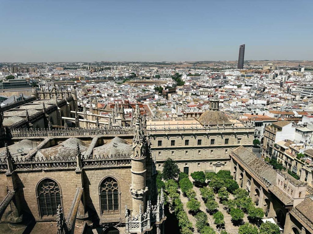 3 Most Amazing Days In Seville, Spain 24 Panoramic aerial view of Seville from the top of the Giralda tower, overlooking the cathedral rooftops, Alcazar gardens, and the cityscape.