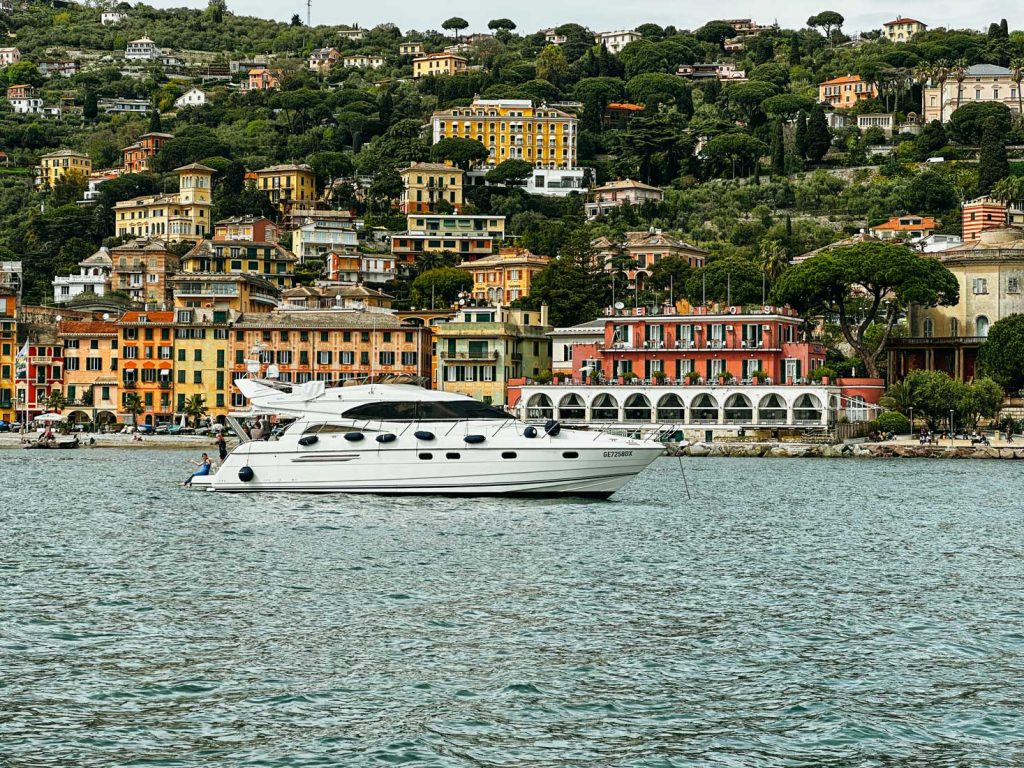 Portofino Or Cinque Terre: Which Is Better? 20 A luxury white yacht floats on the water in front of colorful hillside buildings and a vibrant waterfront promenade in Santa Margherita.