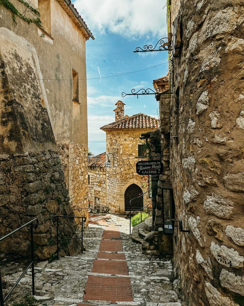 20 Best European Summer Destinations To Visit This Year 26 A narrow cobblestone alley framed by rustic stone buildings leads toward a small arched doorway and gallery sign. The charming old town setting adds timeless appeal to a Europe bucket list itinerary.