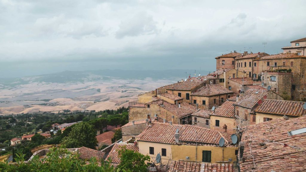 15 Amazing Day Trips From Florence, Italy 27 Cluster of terracotta rooftops sits on a hill under a gray overcast sky with a broad valley fading into mist beyond. The moody weather makes this a strong visual for how to plan travel abroad during uncertainty with backup plans and room for changing conditions.