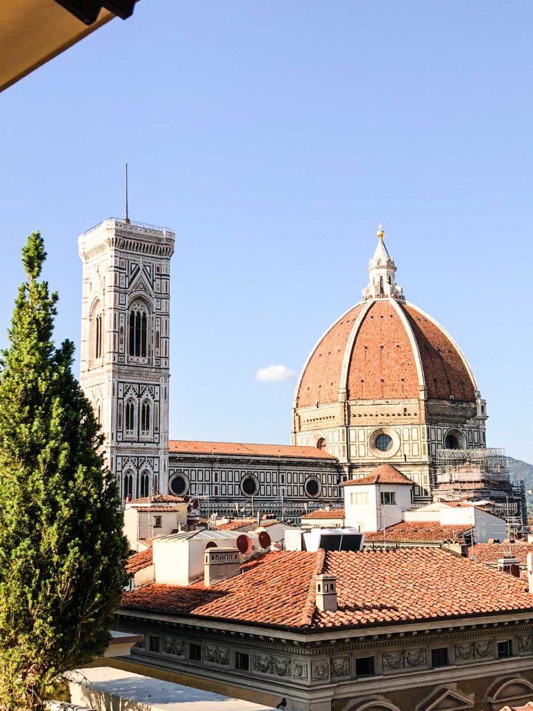The Perfect 3 Day Florence Itinerary (From an Italy Travel Expert) 17 View of Florence Cathedral with Brunelleschi’s red dome and Giotto’s bell tower rising above terracotta rooftops. The cathedral is seen from a higher viewpoint on a clear sunny day.